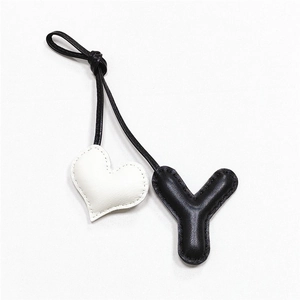Close-up of handmade leather bag charm featuring a black Y letter and white heart detail