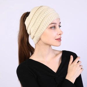 Detail of beige knitted ponytail headband showing soft texture and open top design