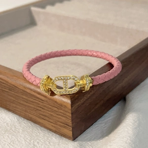 Dettaglio del bracciale in pelle intrecciata rosa con chiusura dorata e diamanti pavé