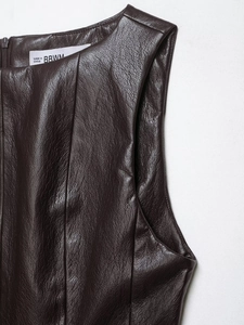 Gros plan sur la texture du cuir marron foncé et l'étiquette de ce haut sans manches