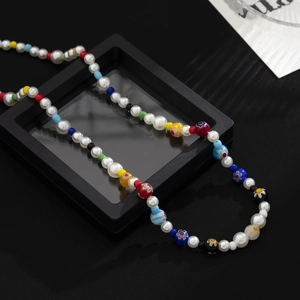 Minimalist necklace featuring colorful glass flower beads and white pearls on a black box