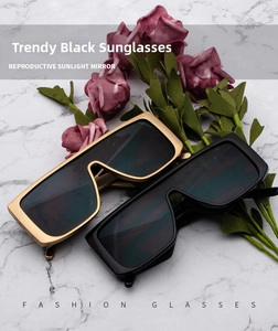 Flat lay of retro oversized square sunglasses in gold and black frames on marble