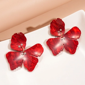 Detail of red marble texture resin butterfly earrings with crystals in a ceramic tray