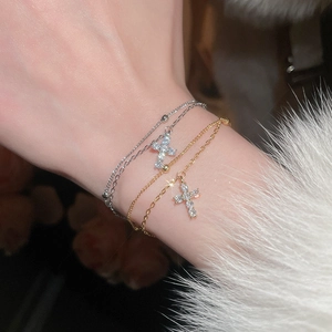 Macro detail of delicate gold and silver cross bracelets with zircon stones on wrist