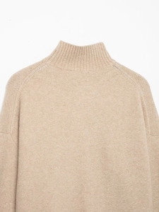 Gros plan du col montant côtelé et des coutures d'épaule d'un pull en maille beige