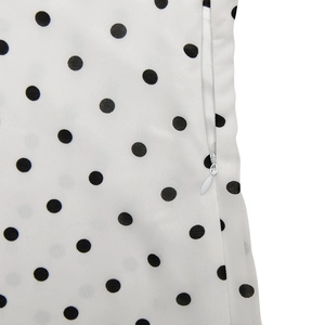 Detailed view of an invisible zipper on a white and black polka dot dress fabric