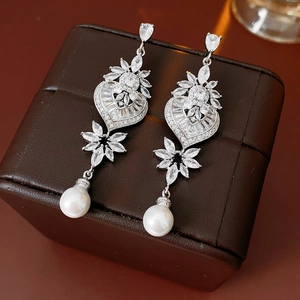 Detail of silver drop earring with crystal heart, leaf pattern and hanging pearl