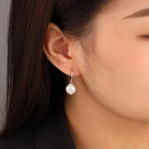 Baroque irregular freshwater pearl earrings with silver hoops worn by a model
