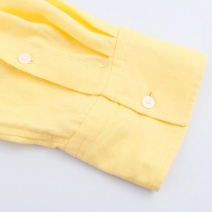 Macro detail of sleeve cuff with two white buttons on yellow linen blend shirt