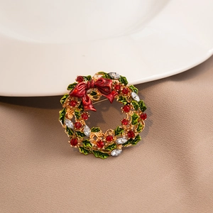 Close-up of a Christmas wreath brooch with red bow and sparkling rhinestones on a white plate