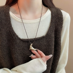 Detailed view of golden croissant pendant on adjustable brown leather cord necklace