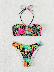 Detailed flat lay of black bikini with vibrant tropical floral patterns and ring detail