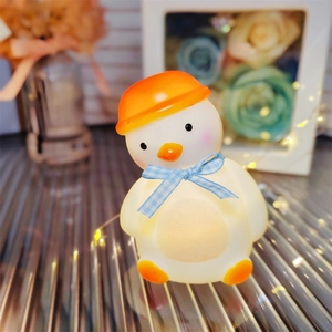 Detail of cute duck night light with orange hat and blue bow emitting warm soft light