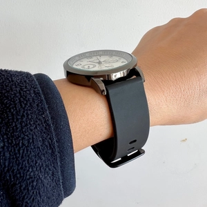Close-up of black silicone strap quartz watch on wrist with detailed silver case dial