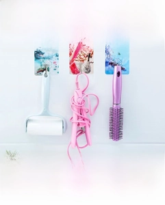 Detail of decorative adhesive wall hooks with artistic landscape patterns and metal hooks