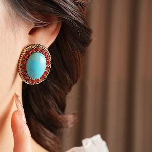 Nahaufnahme von Vintage-Ohrring mit Türkisstein und roten Strasssteinen am Modell