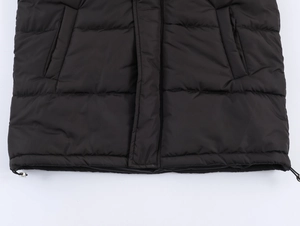 Detail of black hooded puffer jacket showing elastic drawstring hem and quilted texture