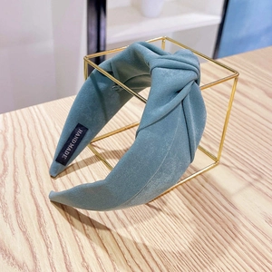 Macro detail of teal fabric headband with stylish top knot and handmade label