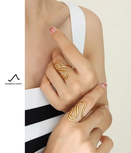 Close-up of golden S-shaped wavy ring on finger showcasing elegant polished steel detail