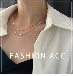 Close-up of double-layer gold chain necklace with white pearls on a model wearing a shirt