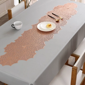 Close-up of rose gold spiderweb table runner with intricate hollow-out texture on grey fabric