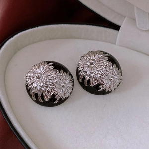 Macro shot of vintage hemisphere stud earrings featuring a silver flower on black enamel