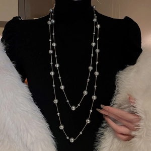 Detail of double-layer station necklace featuring grey pearls on a gold chain