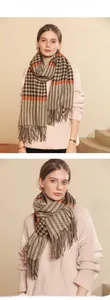 Detail of plaid cashmere-like scarf showing orange contrast stripes and long fringes
