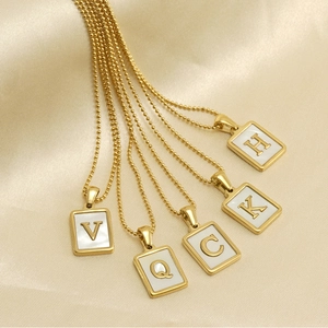 Detail of 18K gold plated square necklaces with white shell inlay and gold letters