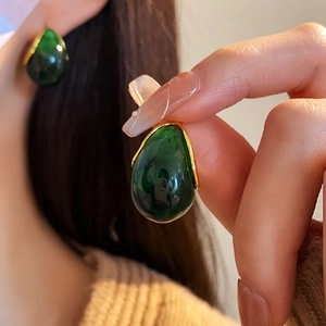 Detail view of a green resin teardrop earring with gold metal trim in French vintage style