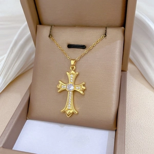 Close-up of gold cross pendant necklace inlaid with white cubic zirconia crystals