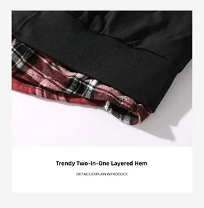 Detailed close-up of the black ribbed hem with red plaid layered faux-two-piece design