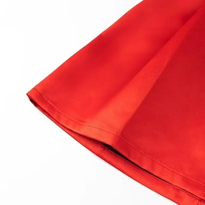 Detailed macro shot of the smooth red satin fabric hem and seamless stitching of the dress