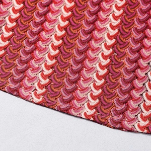 Macro shot of colorful knit fabric showing wave texture in red pink and purple tones