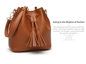 Detail view of tan PU bucket bag with long tassels, drawstring closure and gold hardware