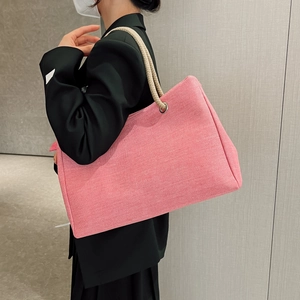 Pink linen tote bag with beige braided rope handle shown worn by a model in a side view