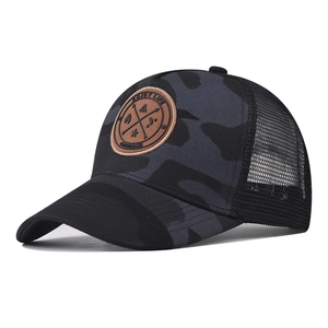 Detail of a camo trucker hat featuring a round leather patch with ENJOY LIFE text