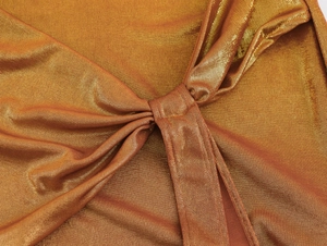 Vue macro d'un tissu en maille dorée métallisée avec un détail de nœud sur une robe de fête