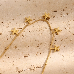 Macro shot of 18K gold plated starfish pendants on a flat snake chain anklet