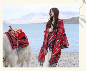 Poncho ethnique rouge à capuche avec pompons et broderie géométrique au bord d'un lac
