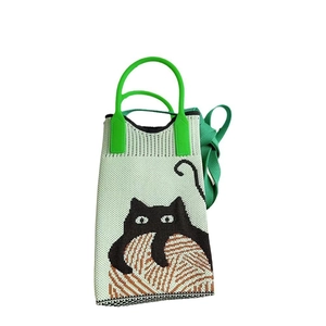 Close-up of a green knitted phone bag featuring a cute black cat and yarn ball pattern