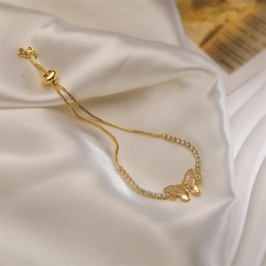 Gros plan du bracelet papillon doré avec strass sur un fond de satin de soie blanc
