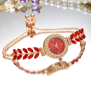 Detail of rose gold quartz watch featuring red leaf gems and sparkling diamond bezel