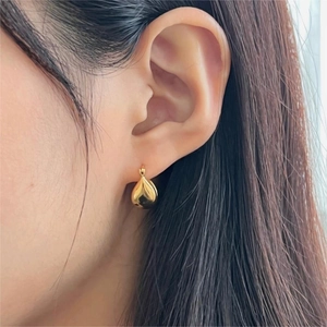 Close-up of elegant gold teardrop hoop earrings with high-polish finish on a model