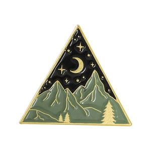 Detail of a triangle enamel pin featuring green mountains and gold crescent moon