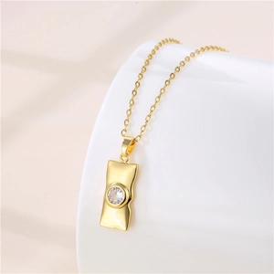 Detailed view of rectangle gold pendant necklace with central zircon on white pedestal