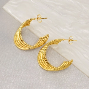 Minimalist gold twisted hoop earrings with textured finish on a stylish ripple background