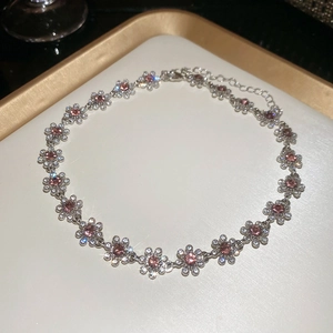 Detail of silver floral necklace with pink gemstones and sparkling crystal accents on a tray