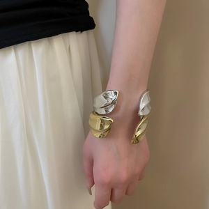 Detail of minimalist irregular metallic wave bangles in gold and silver finishes