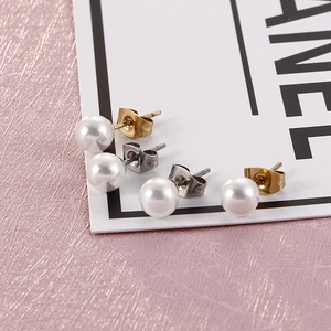 Detail of round pearl stud earrings in gold and silver settings on a display card